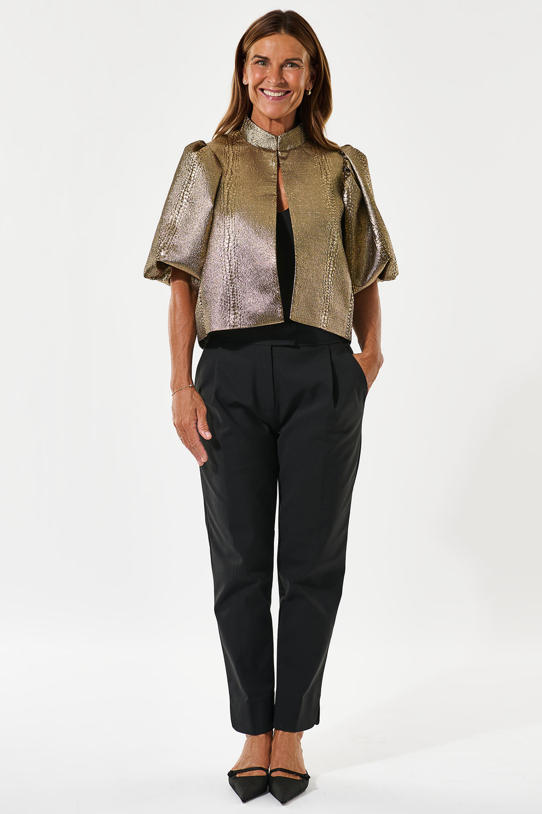 Woman wearing a metallic top and black pants on a white background