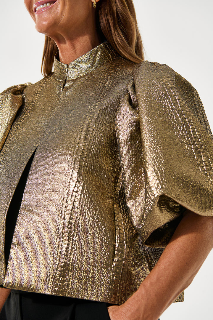 Gold metallic top worn by a person on a white background