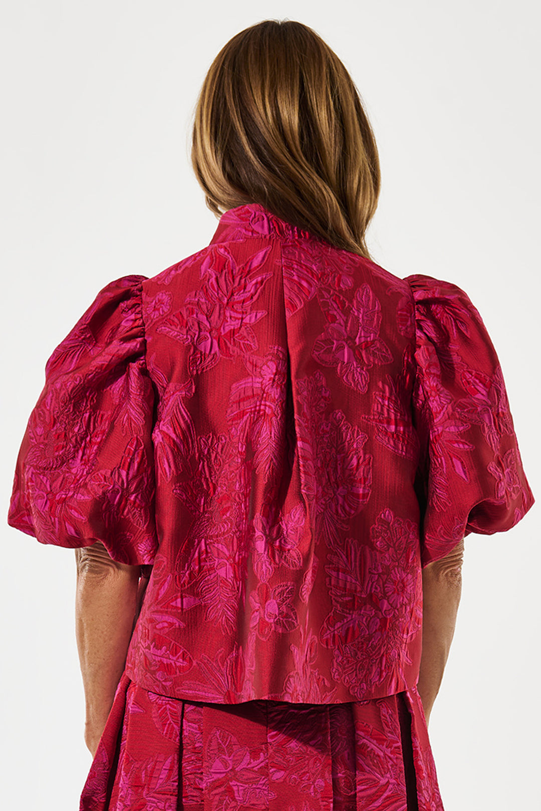 Person wearing a red textured dress with puff sleeves on a white background