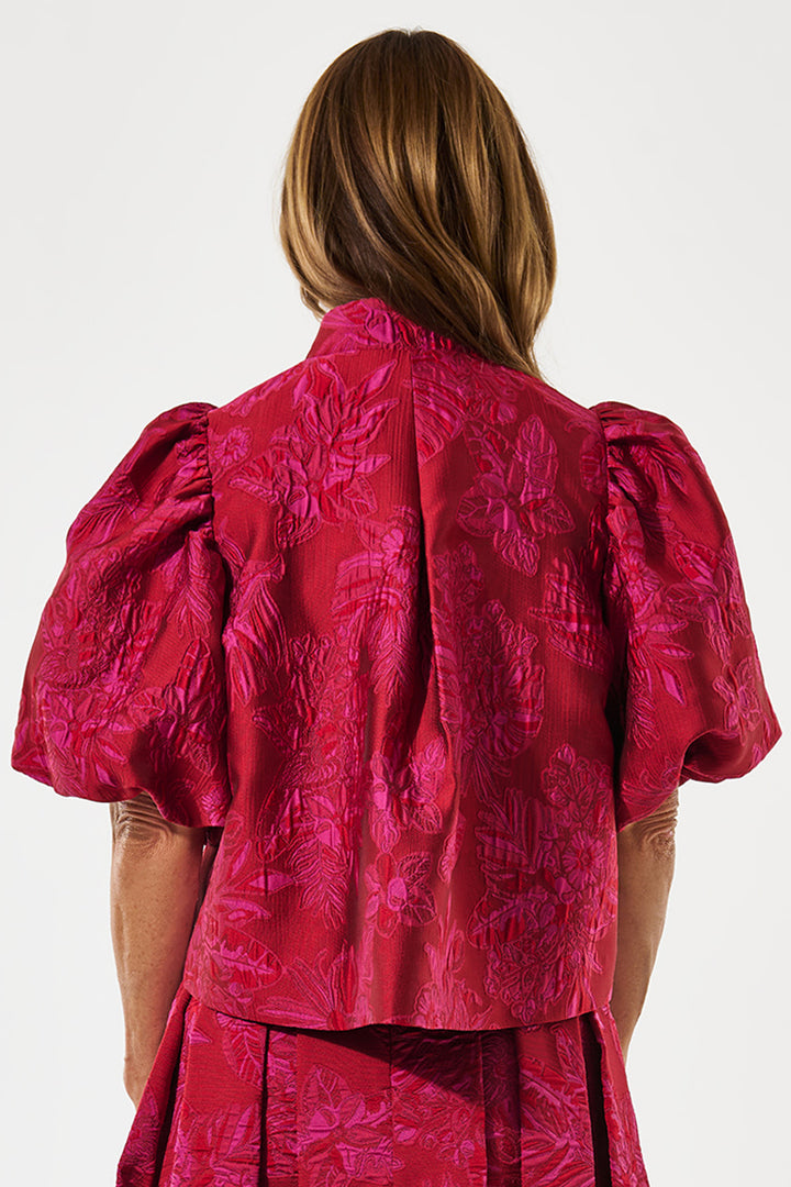 Person wearing a red textured dress with puff sleeves on a white background