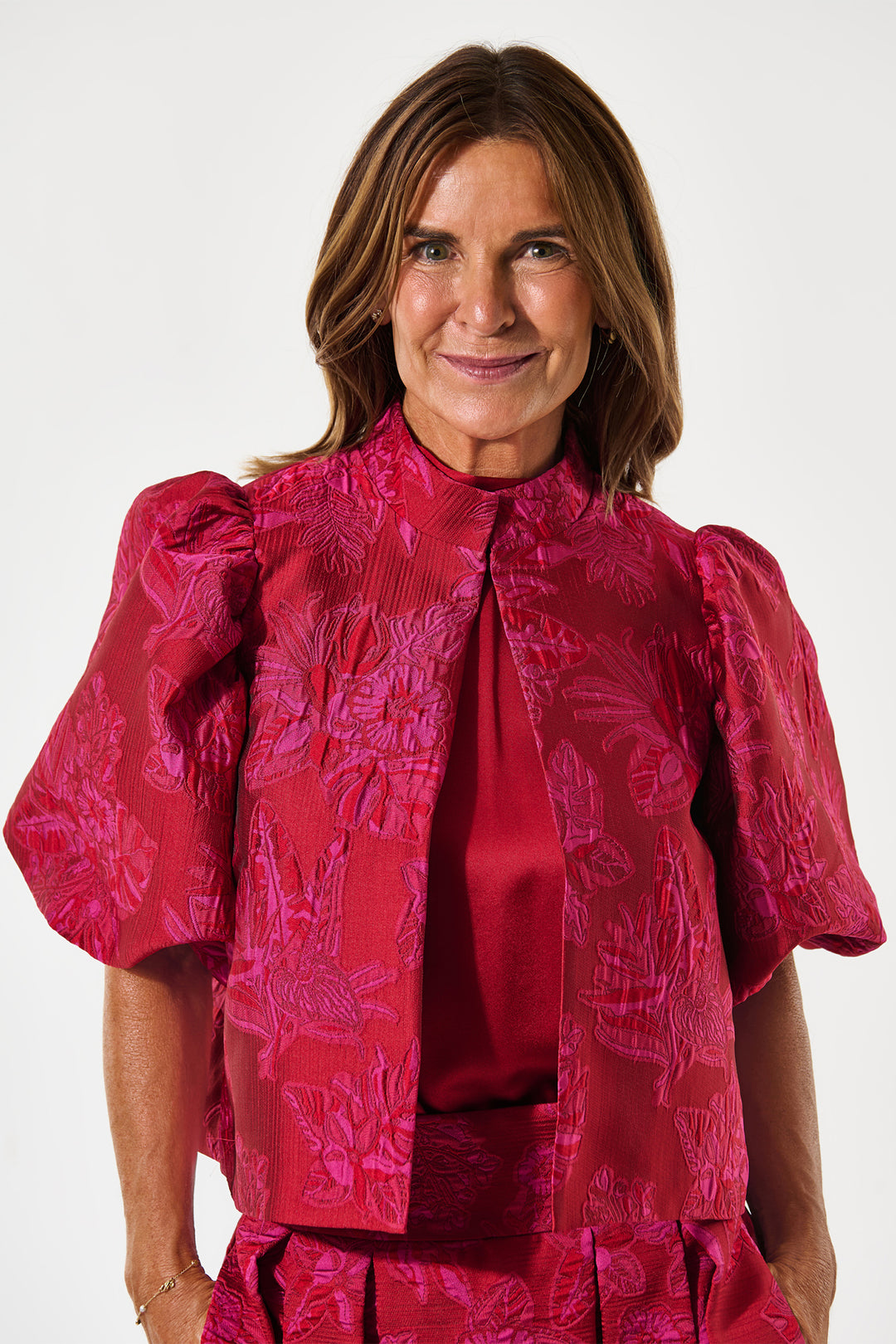 Woman wearing a red patterned blouse against a white background