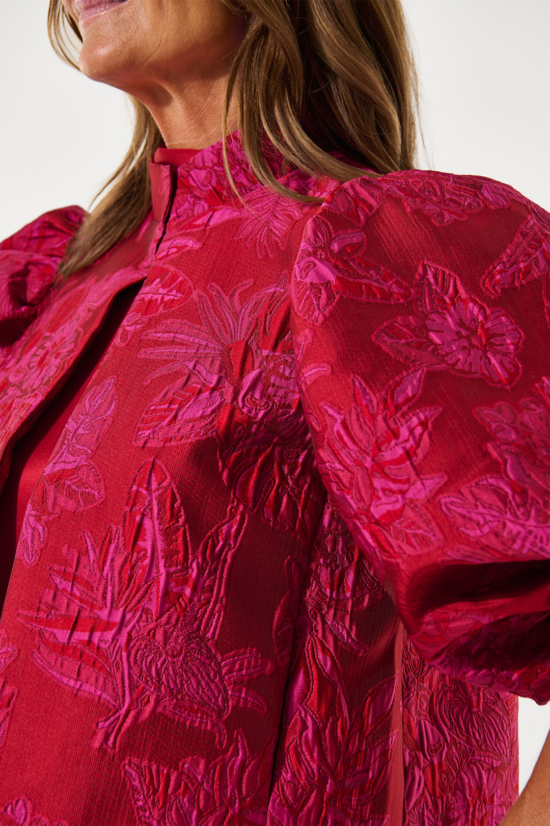 Close-up of a person wearing a red floral blouse with puff sleeves.