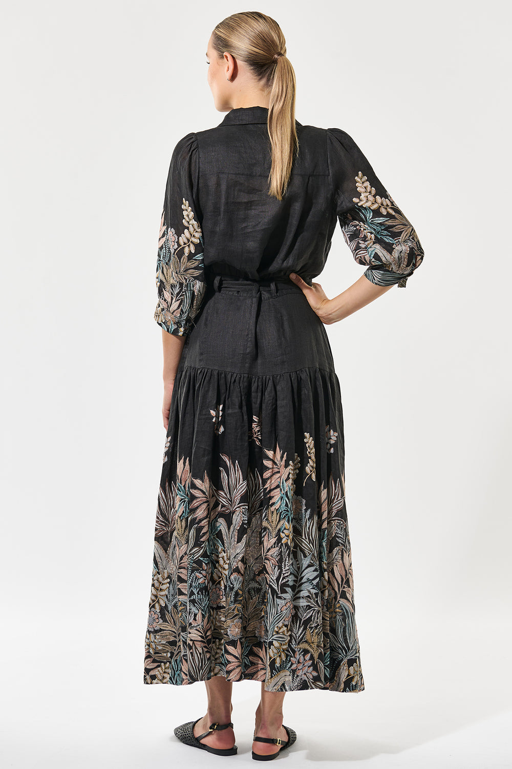 Woman wearing a black dress with floral patterns on a white background