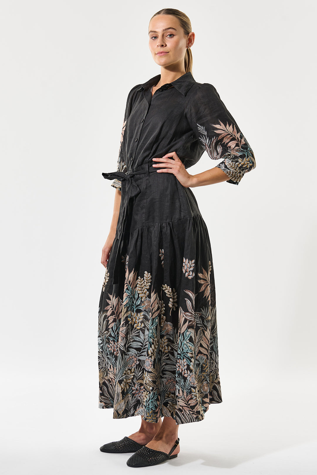 Woman wearing a black dress with floral patterns on a white background