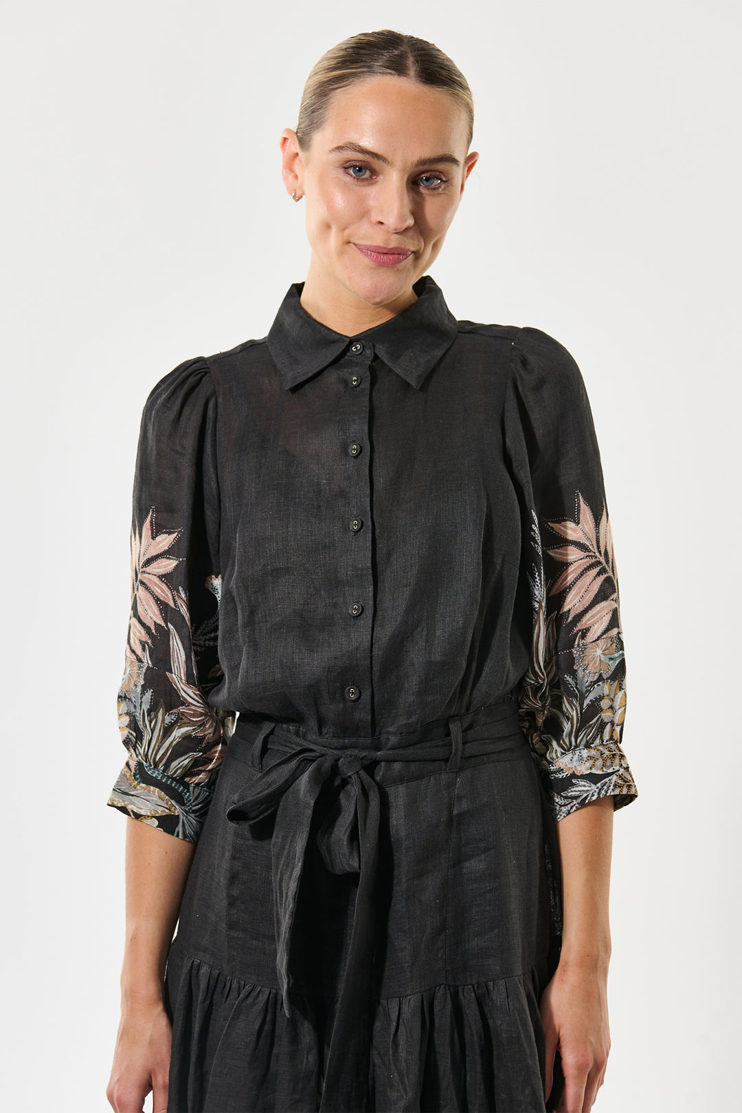 Woman wearing a black blouse with floral sleeves against a white background