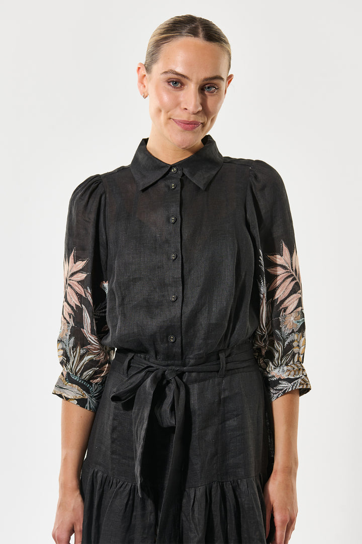 Woman wearing a black blouse with floral sleeves against a white background