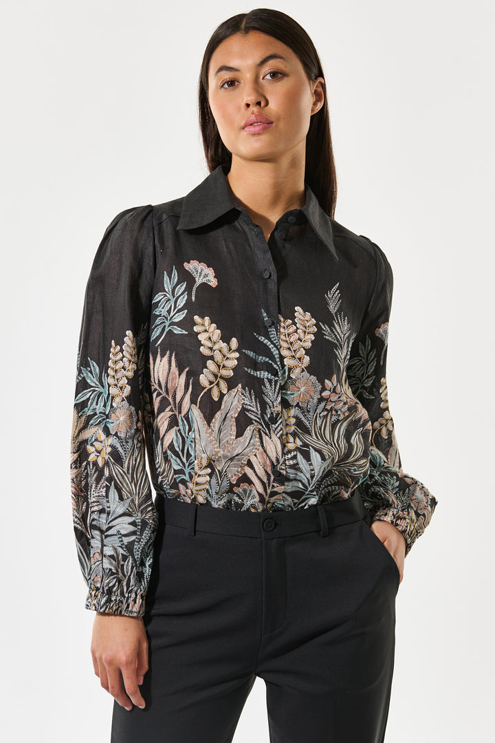 Woman wearing a black floral blouse against a white background