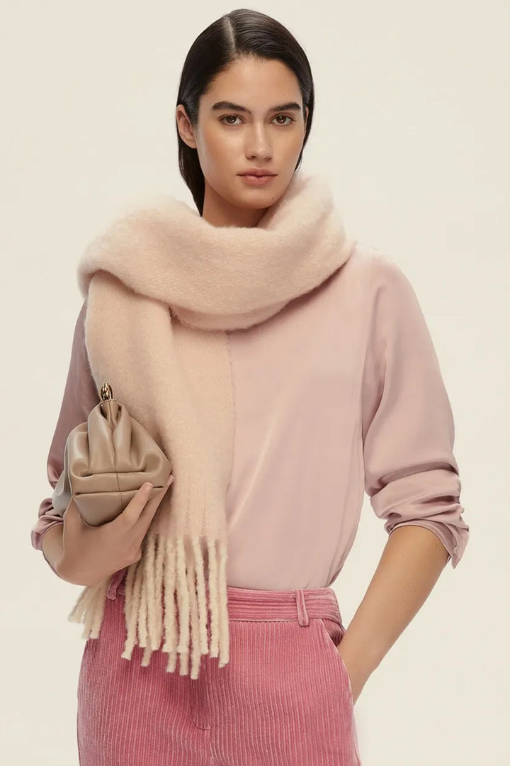 Woman wearing a pink sweater and beige scarf on a beige background