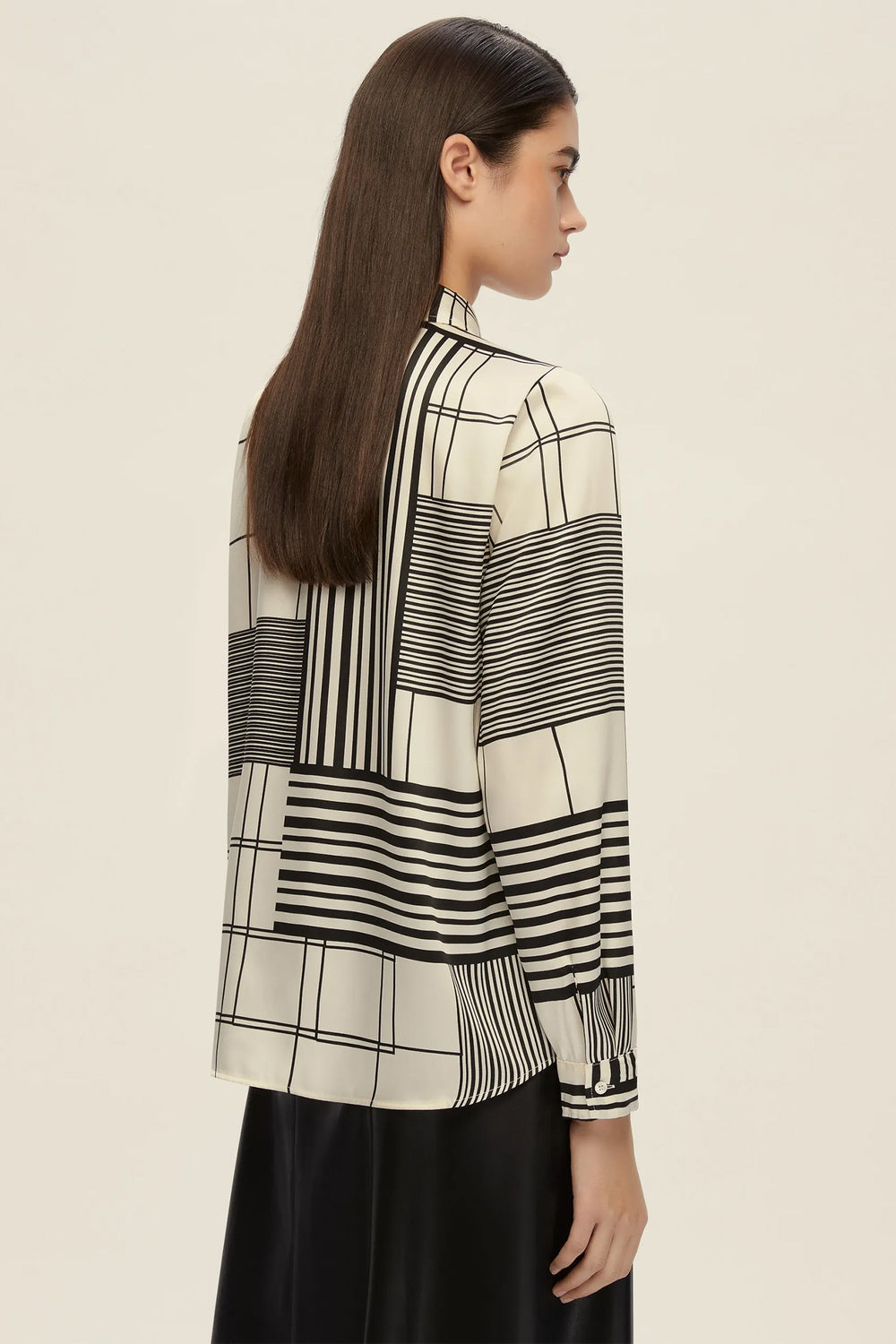 Woman wearing a black and white patterned blouse against a beige background