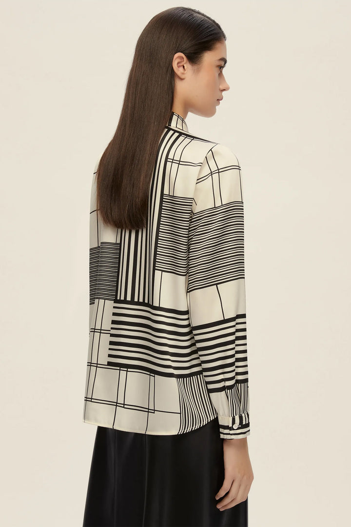 Woman wearing a black and white patterned blouse against a beige background