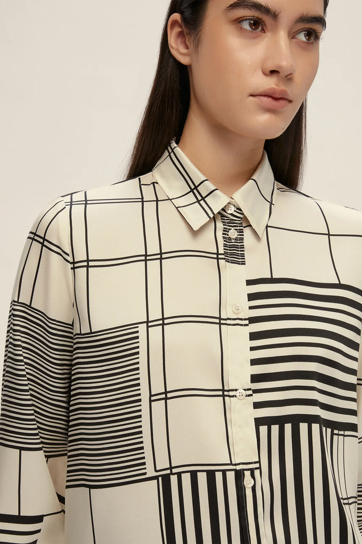 Person wearing a black and white checkered shirt with vertical stripes on a plain background