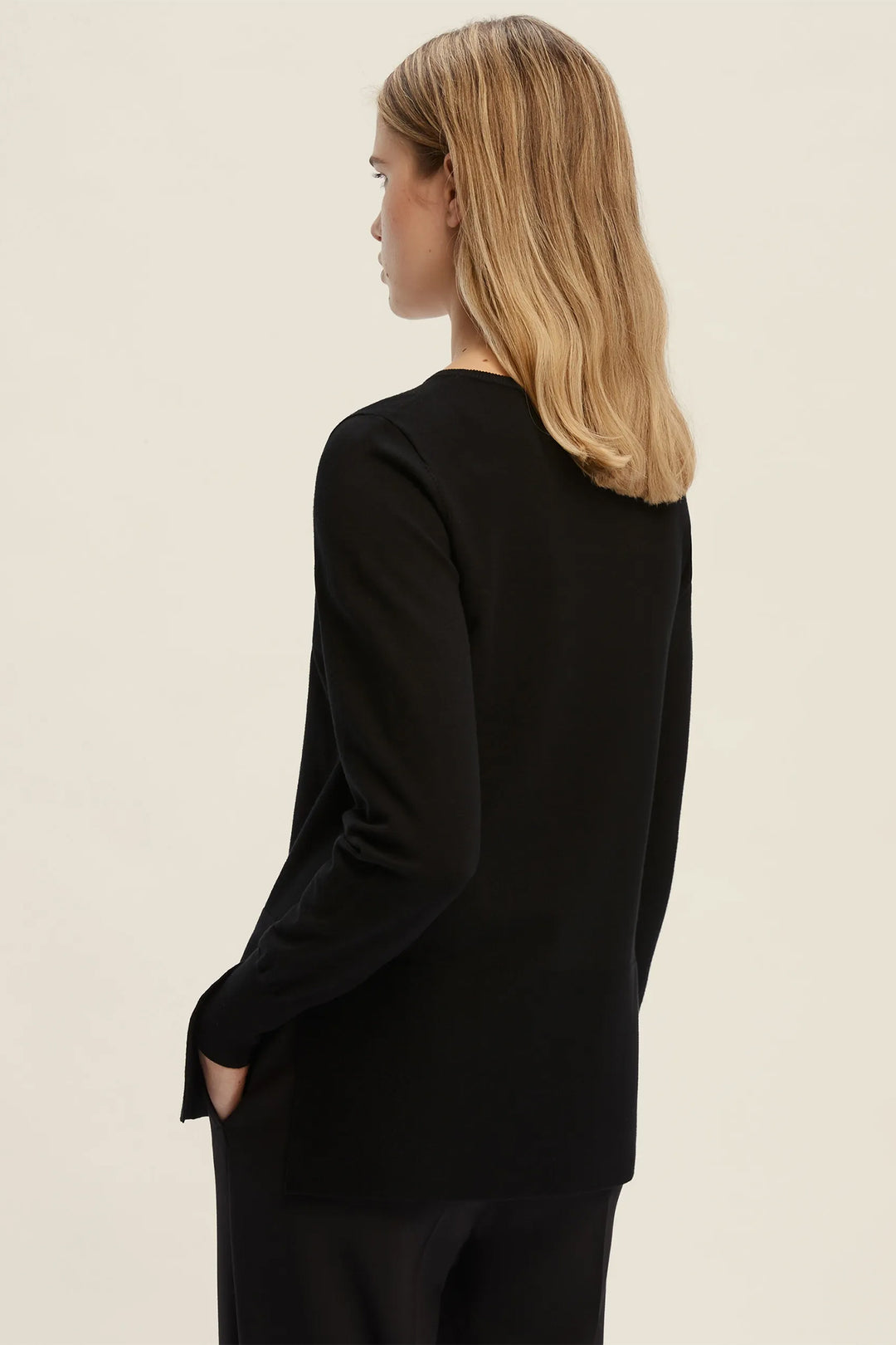 Person wearing a black long-sleeve top on a beige background