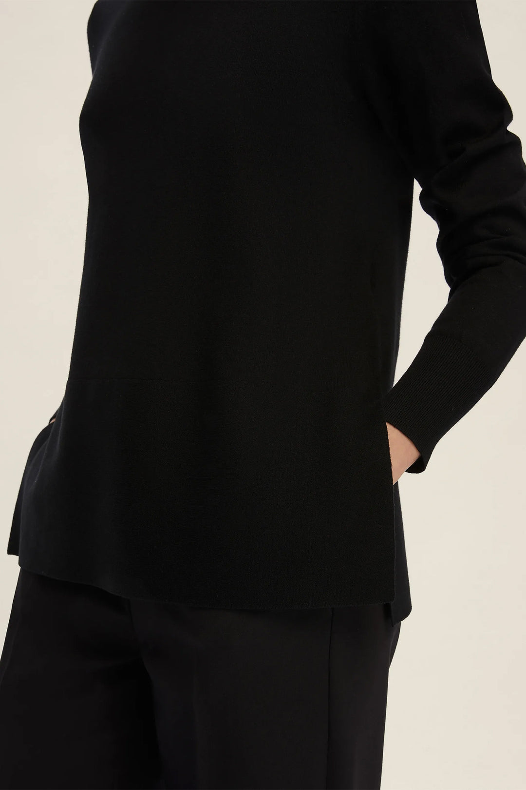 Black suit jacket and pants on a beige background