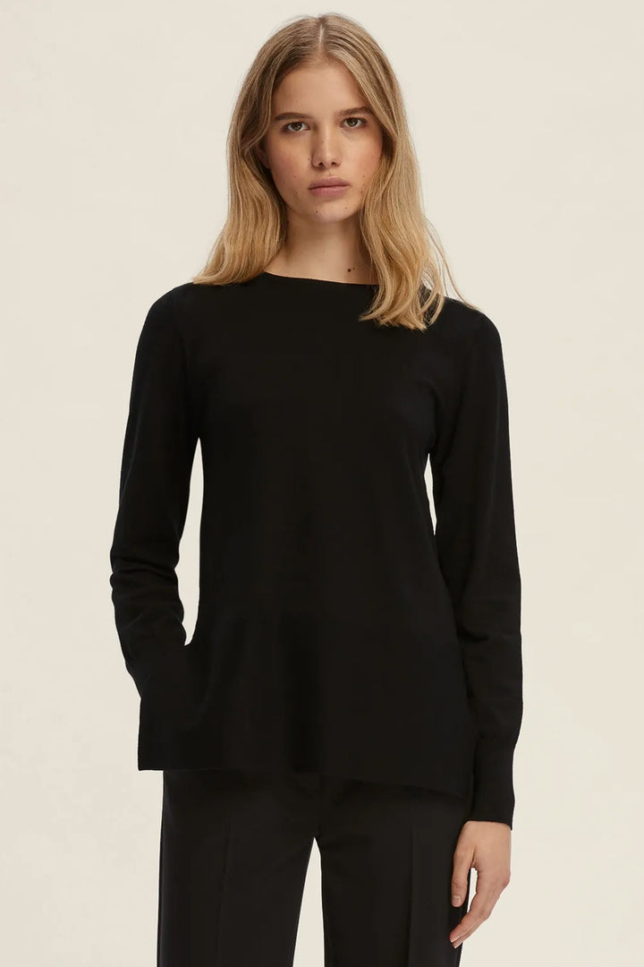 Woman wearing a black long-sleeve top against a beige background