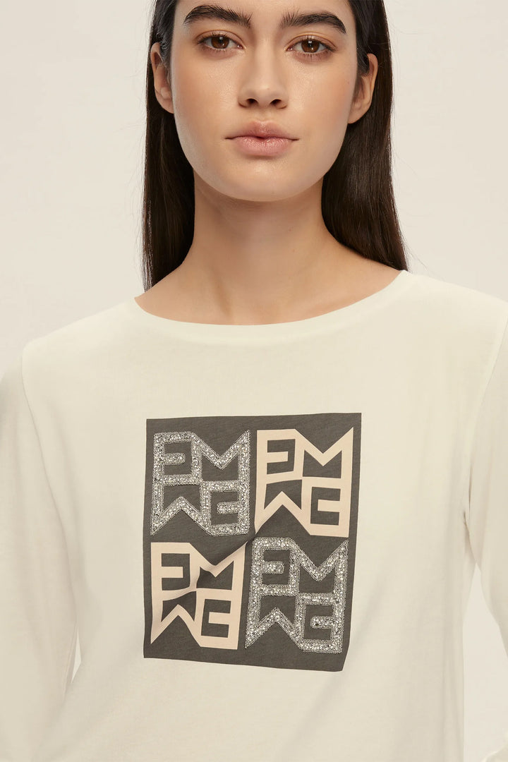 Woman wearing a white sweater with a black and gray patterned design on a plain background