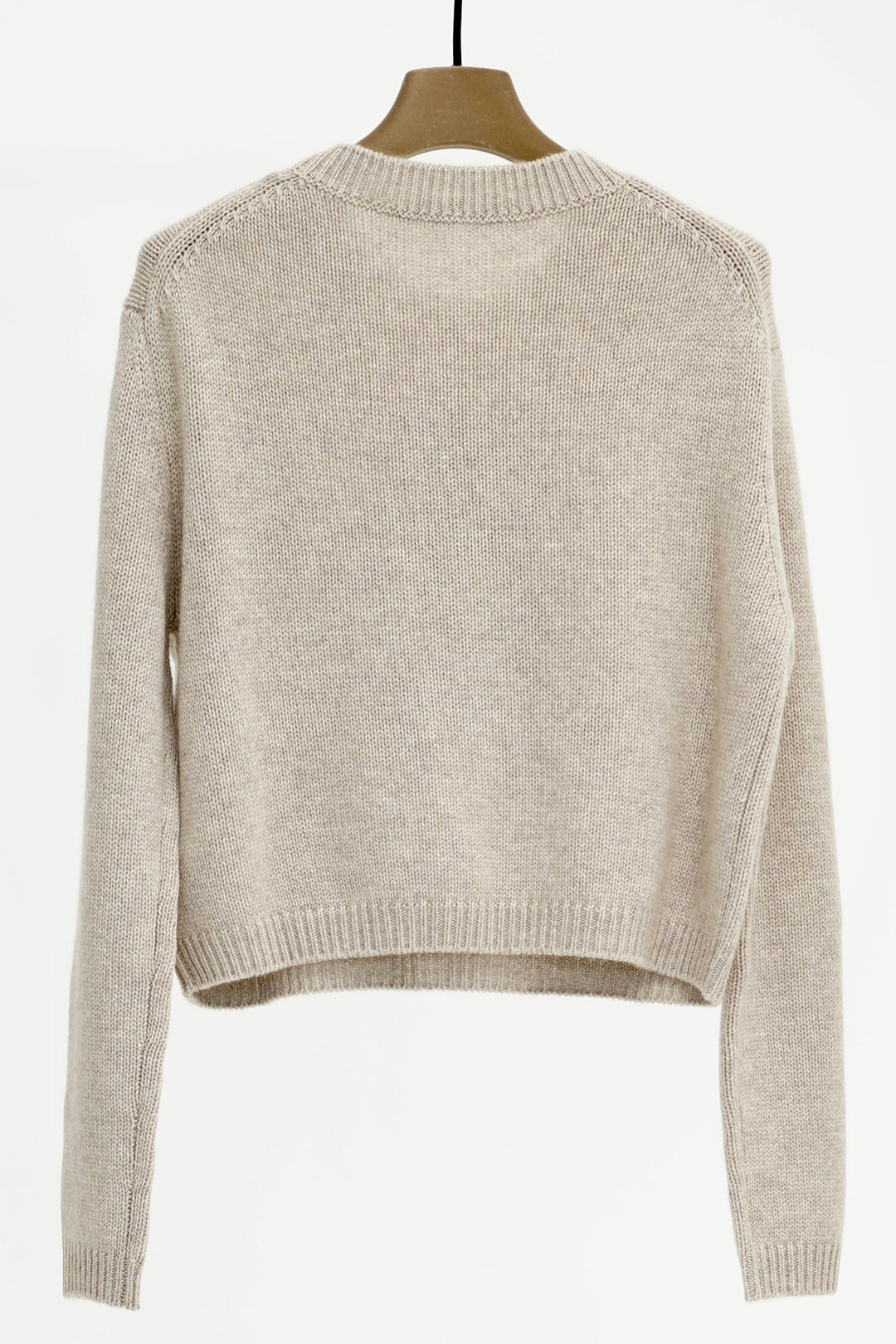 Beige sweater on a wooden hanger against a white background