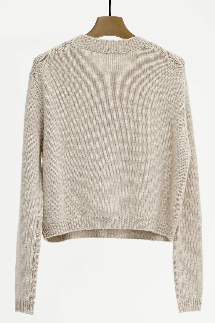 Beige sweater on a wooden hanger against a white background