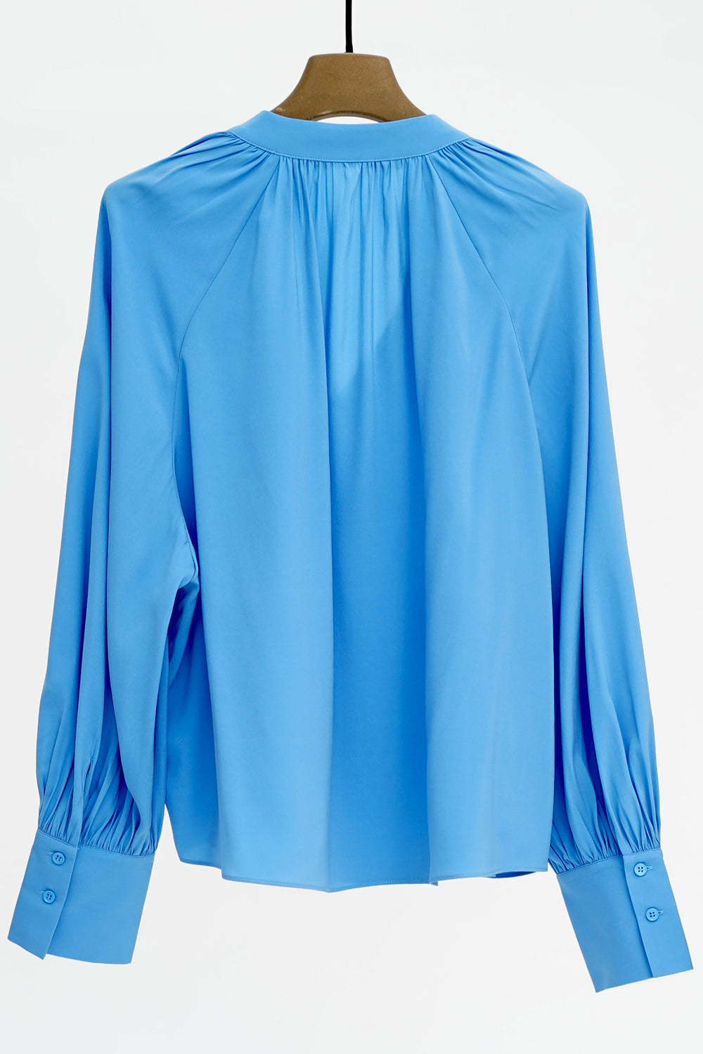 Blue blouse on a hanger against a white background