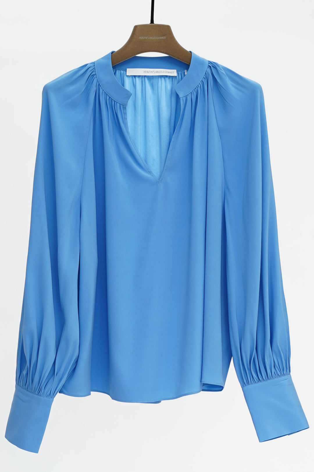Blue blouse on a hanger against a white background