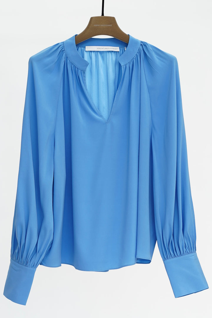 Blue blouse on a hanger against a white background