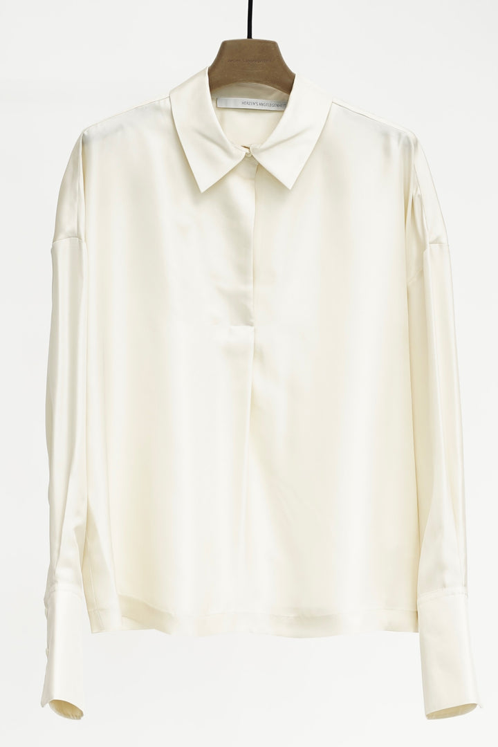 Cream shirt on a wooden hanger against a white background