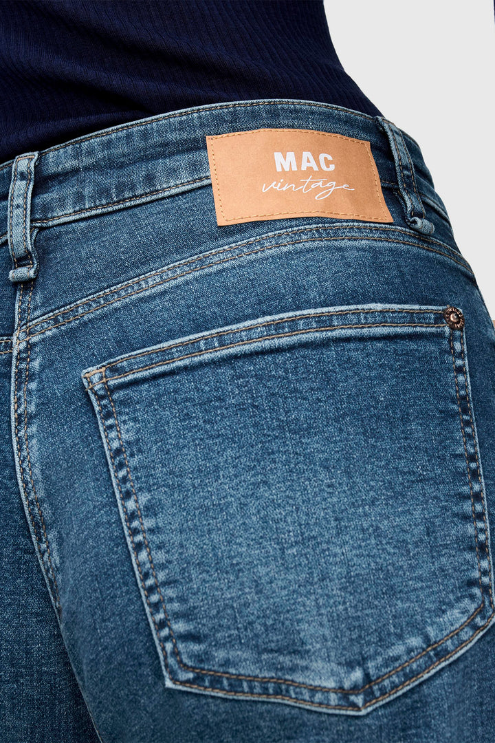 Blue jeans with a brand label on the back pocket against a white background