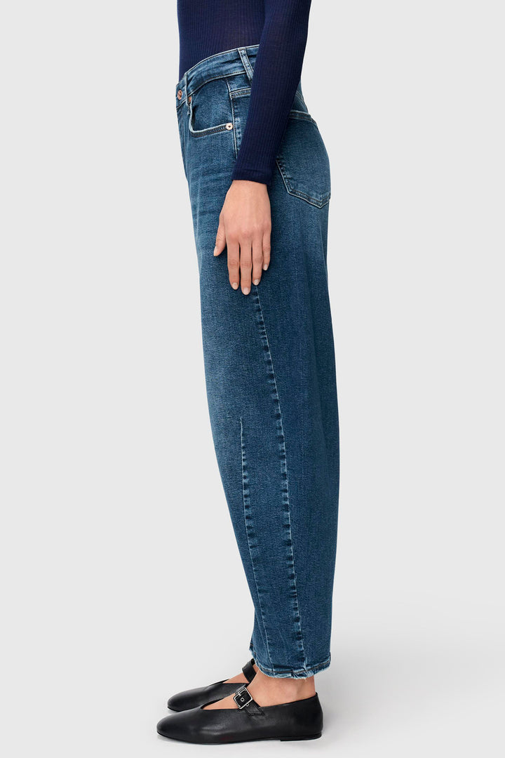 Person wearing blue jeans and black shoes on a white background