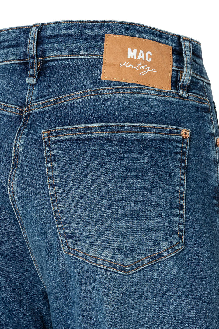 Close-up of blue jeans with a visible MAC Vintage label on a white background