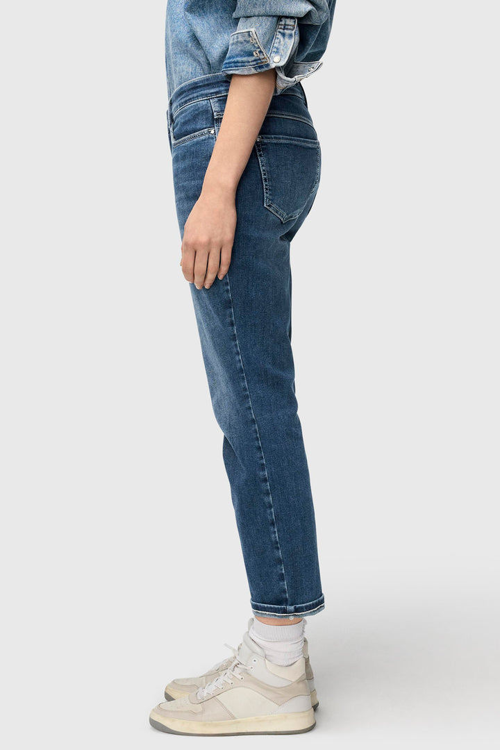 Person wearing blue jeans and white sneakers on a white background