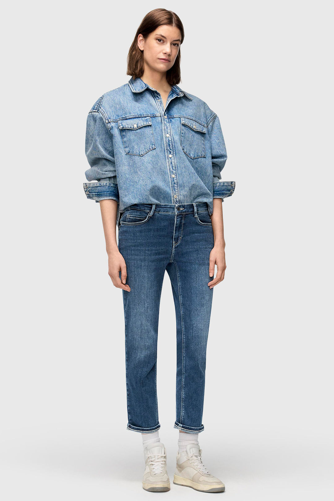 Person wearing a denim jacket and jeans on a white background