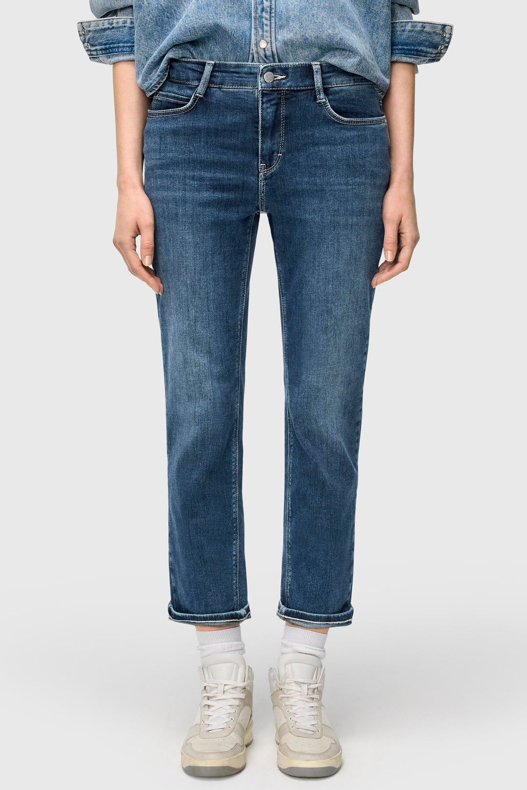 Person wearing blue jeans and a denim shirt on a white background