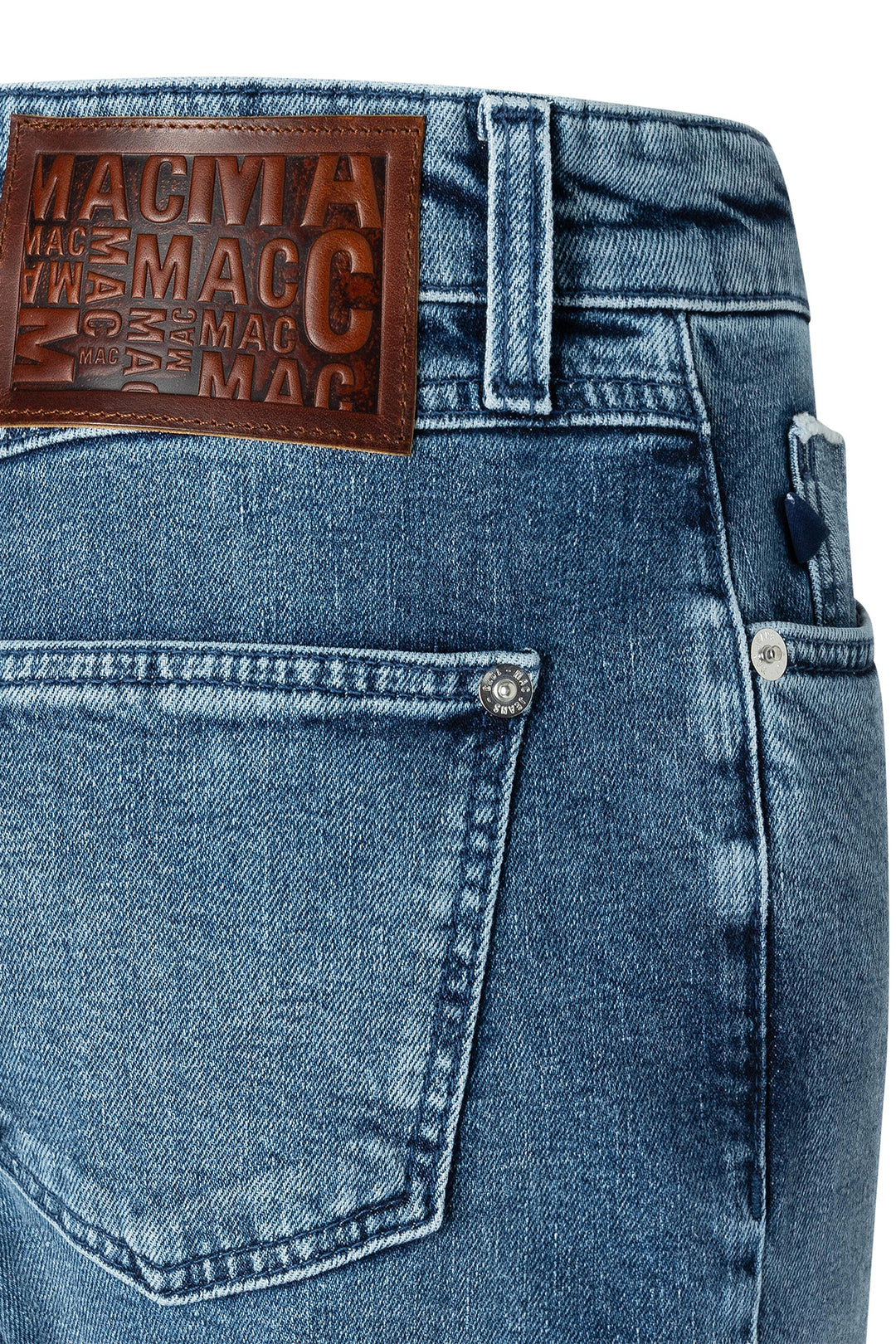 Close-up of blue jeans with a brown leather patch displaying 'MAC'.