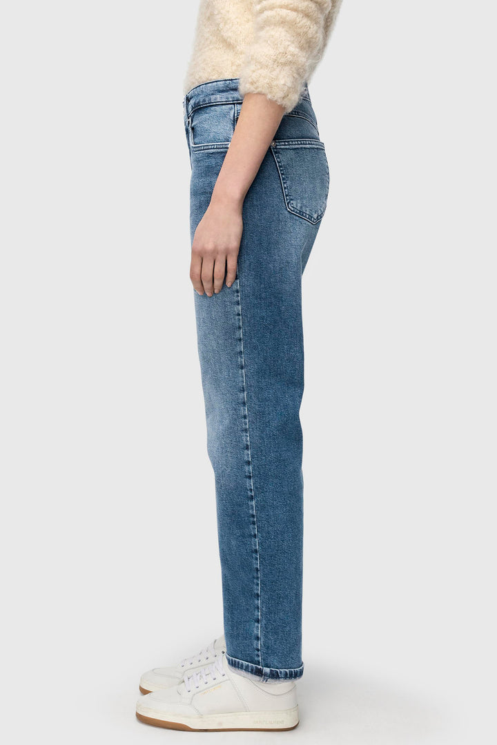 Person wearing blue jeans and a cream sweater on a white background