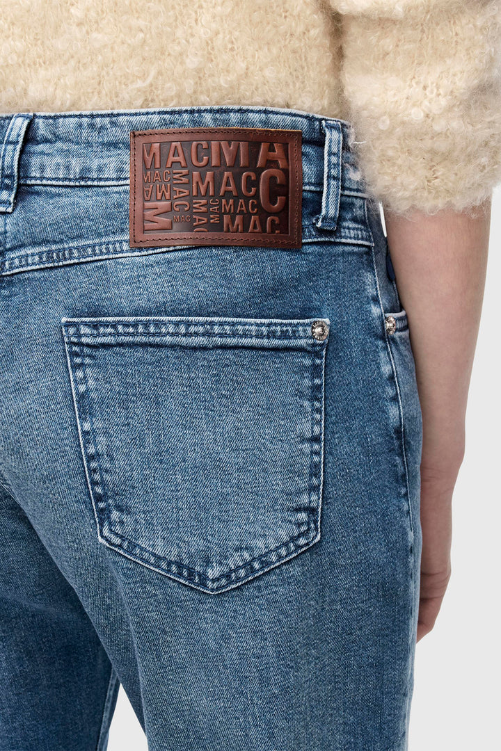 Blue jeans with a brand label on the back pocket against a neutral background