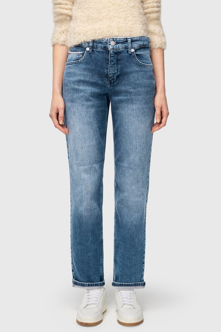 Person wearing blue jeans and a beige sweater on a white background