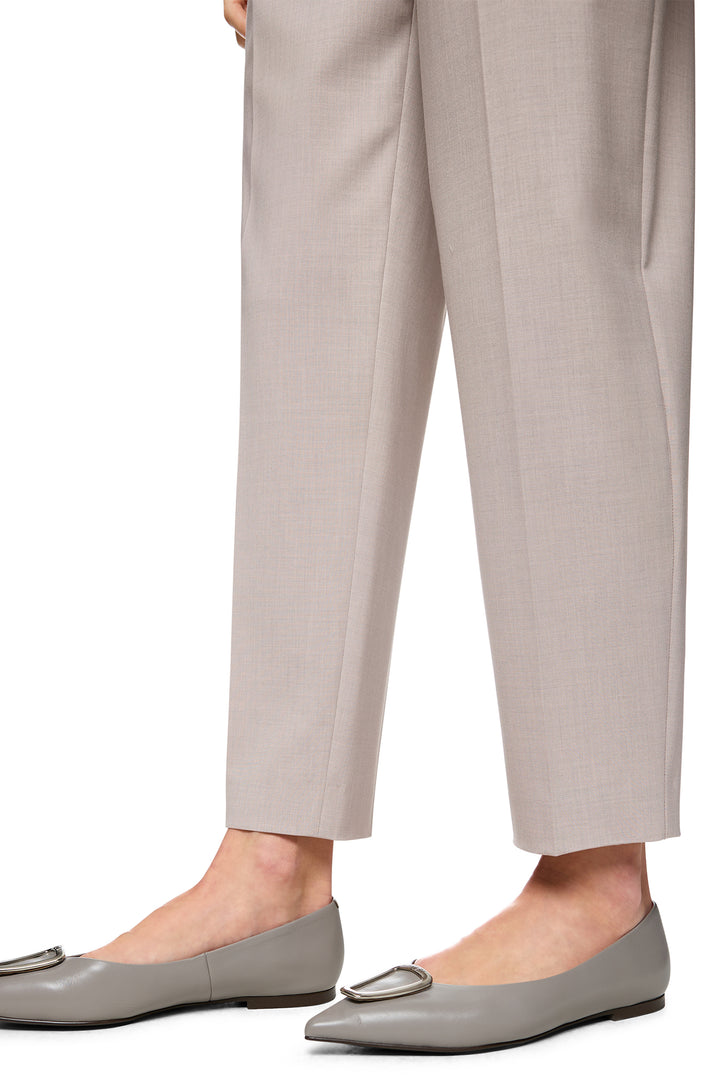 Close-up of beige pants and gray flats on a white background