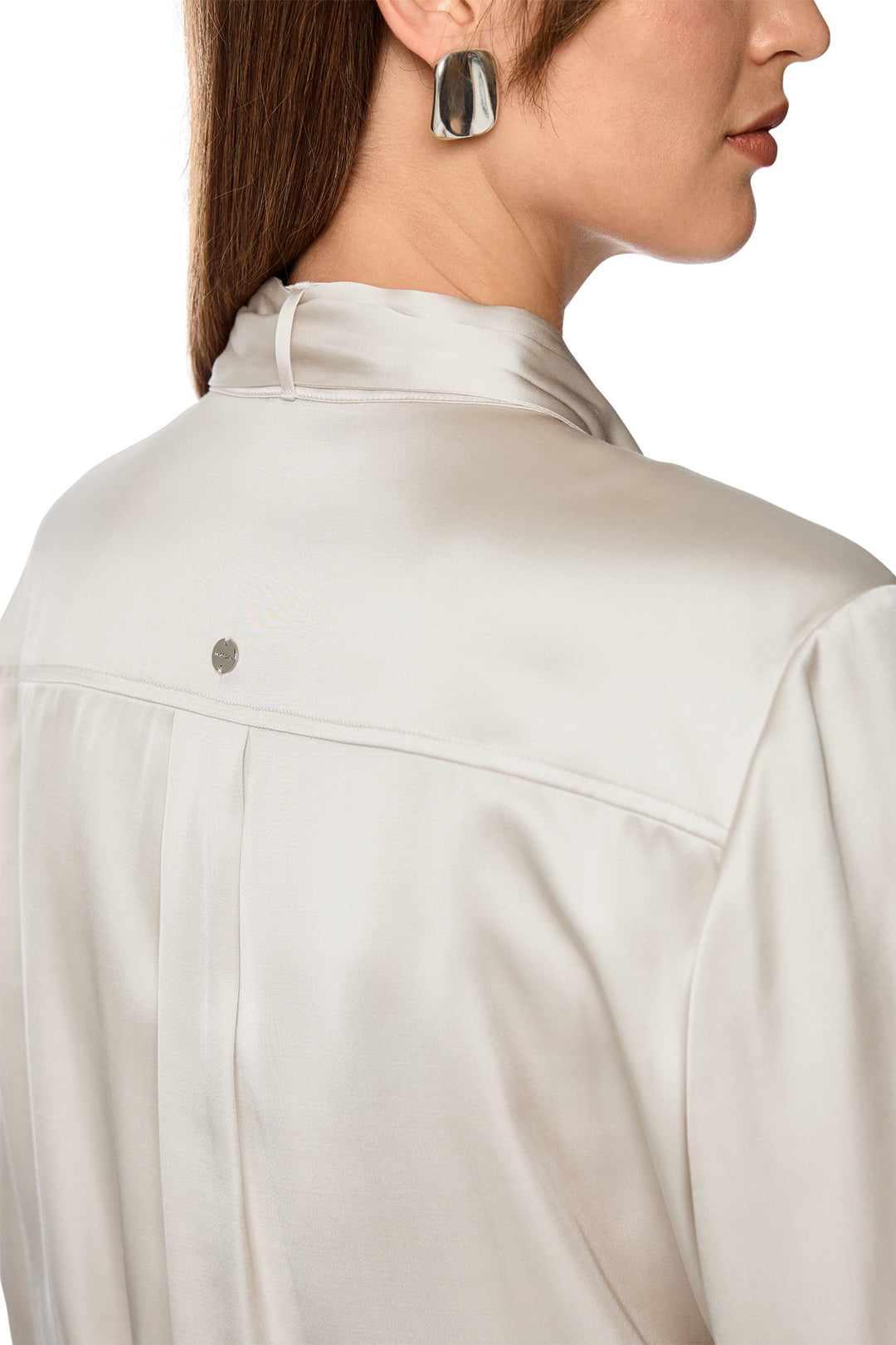 Close-up of a person wearing a light-colored jacket with a focus on the collar area.