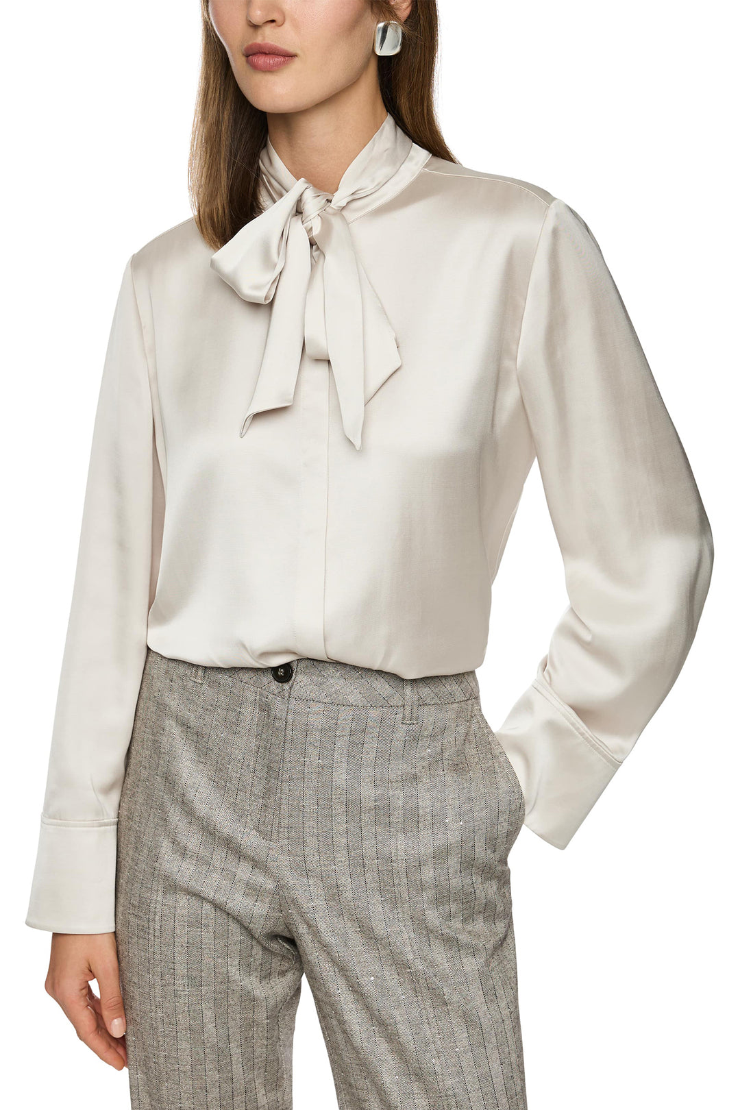 Woman wearing a white blouse with a tie neckline and plaid pants on a white background