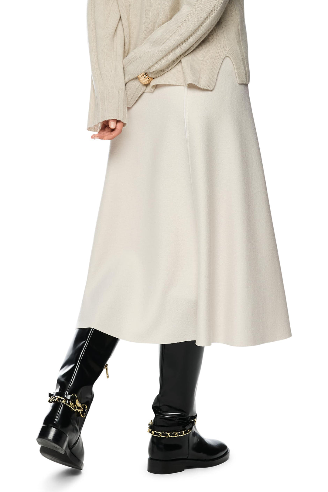 Person wearing a long beige coat and black boots on a white background