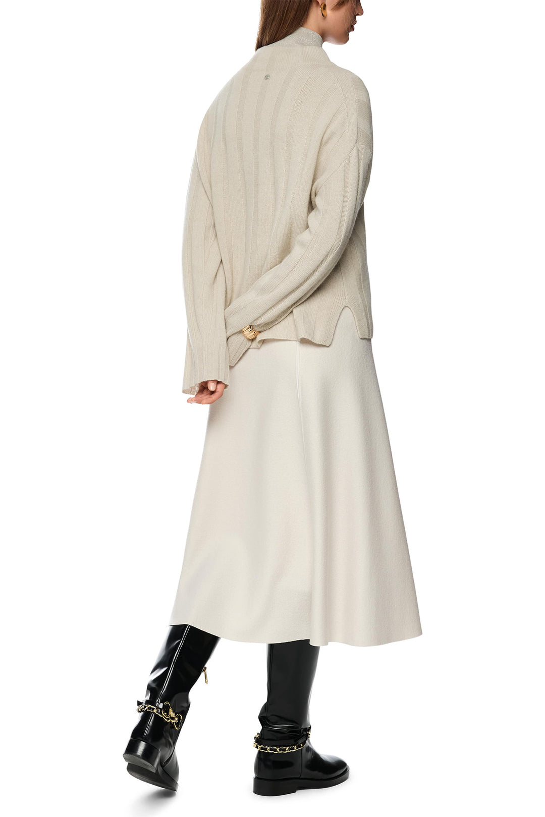 Person wearing a long beige coat and black boots on a white background