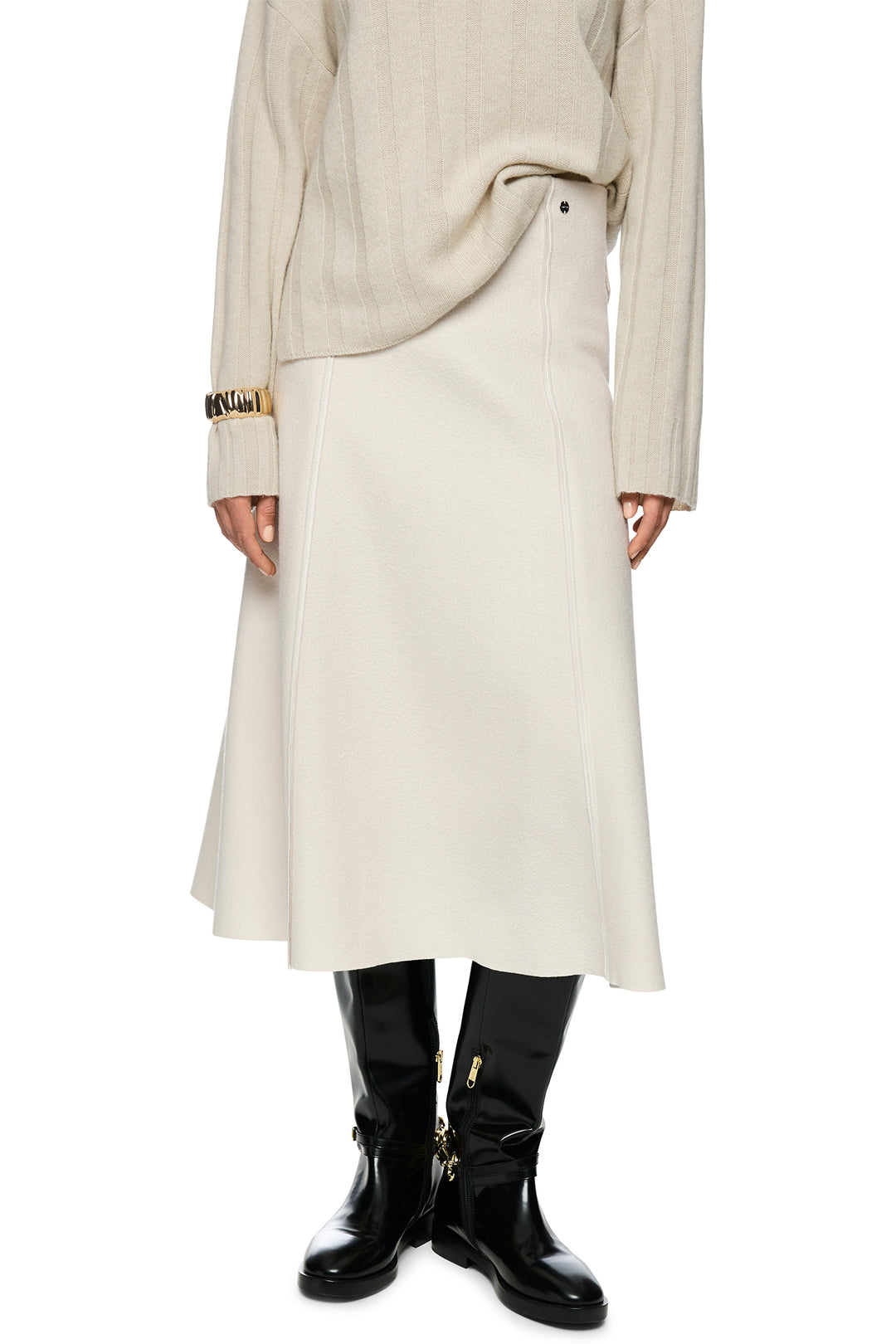 Person wearing a long beige coat and black boots on a white background