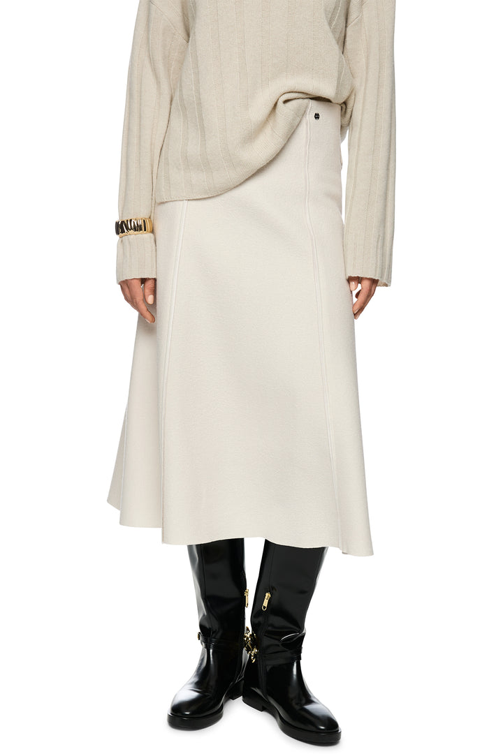 Person wearing a long beige coat and black boots on a white background