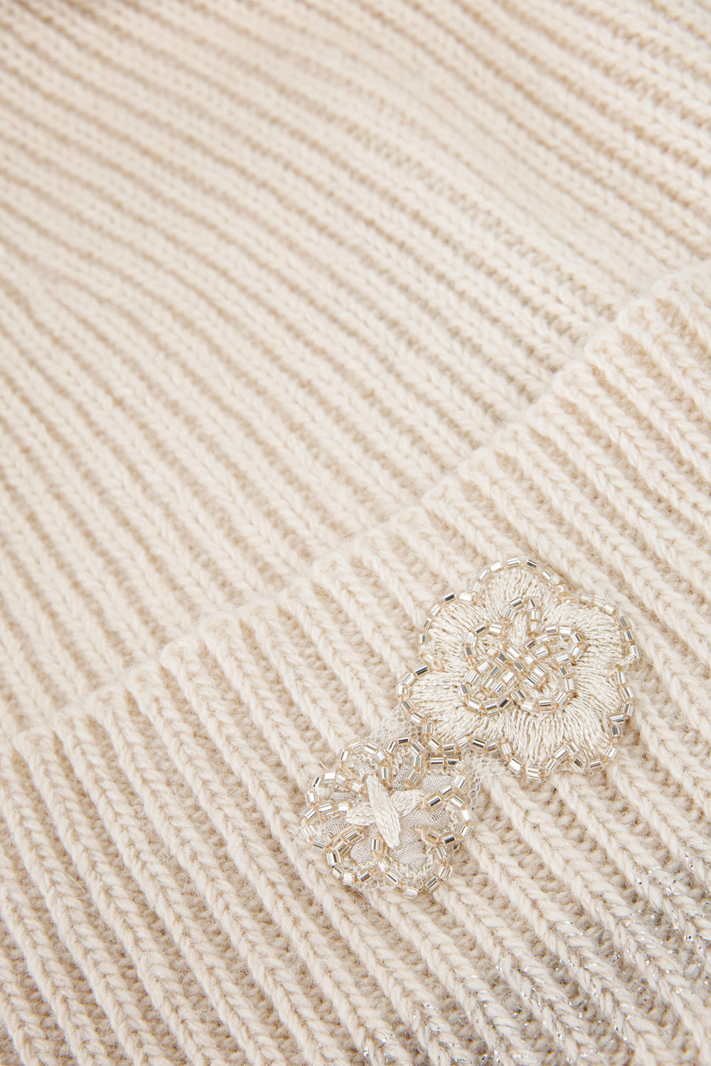 Silver ring with floral design on a beige textured fabric background