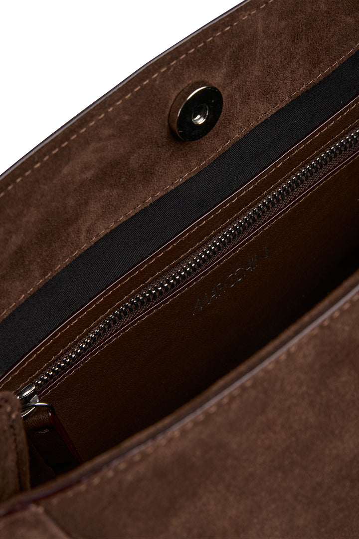 Close-up of a brown leather bag with a zipper, featuring the brand name 'Marc Cain'.