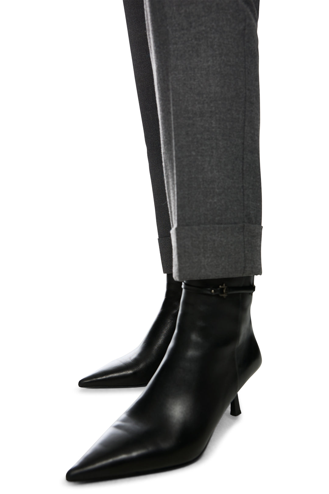 Black leather ankle boots worn with gray pants on a white background