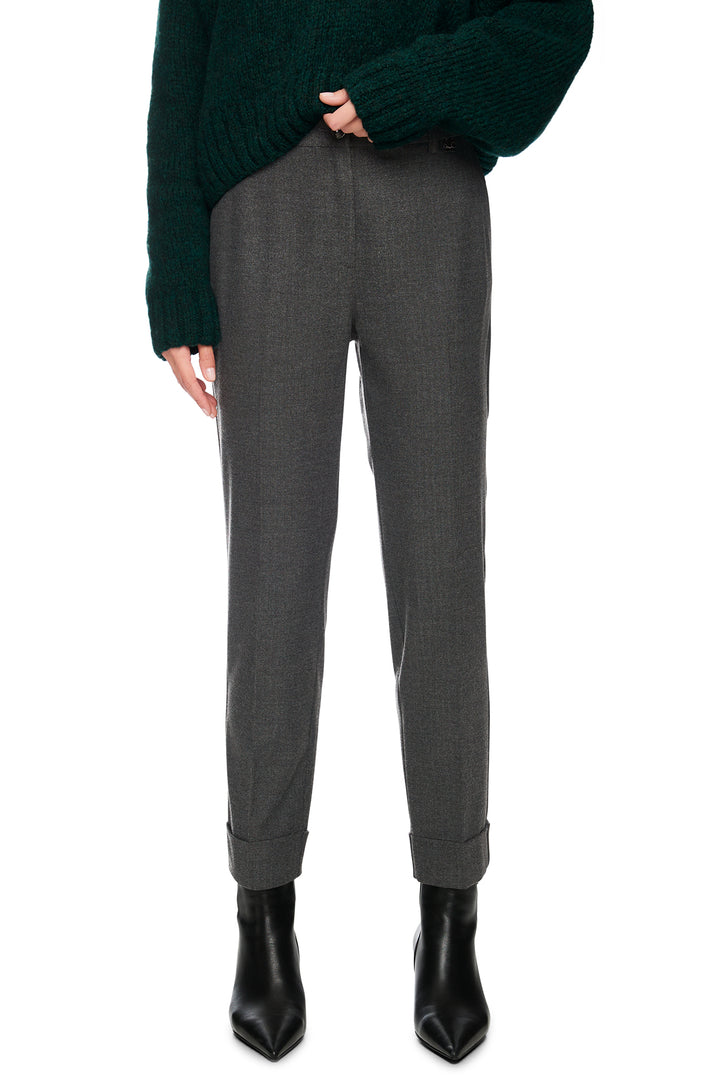 Gray pants worn with a dark green sweater and black boots on a white background