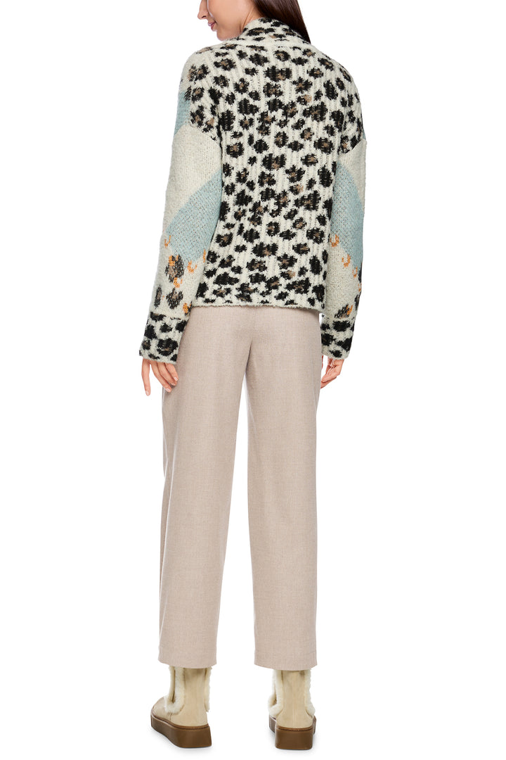 Person wearing a patterned jacket and beige pants on a white background