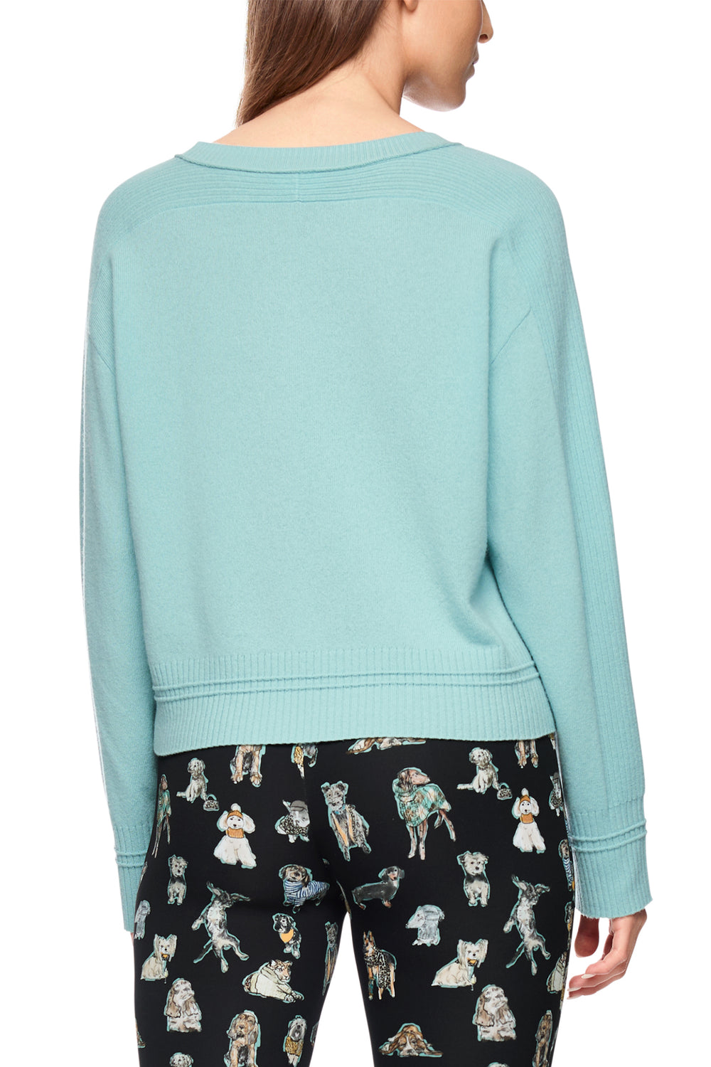 Light blue sweater worn by a person with black pants featuring dog prints on a white background