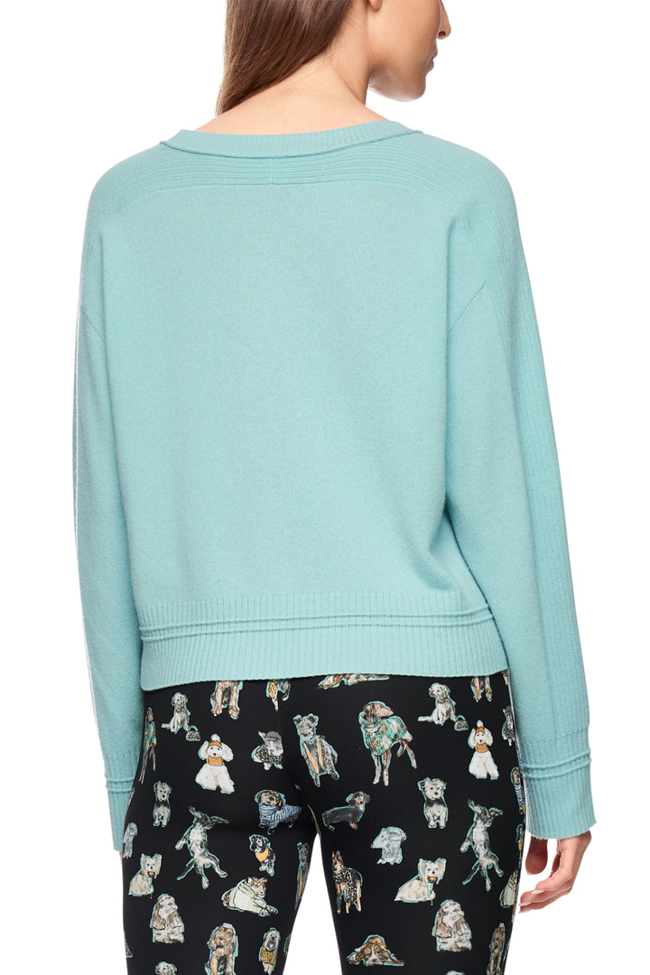 Light blue sweater worn by a person with black pants featuring dog prints on a white background