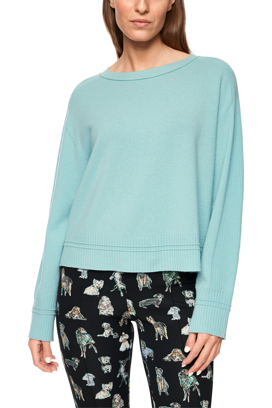 Light blue sweater worn by a person with black pants featuring dog prints on a white background